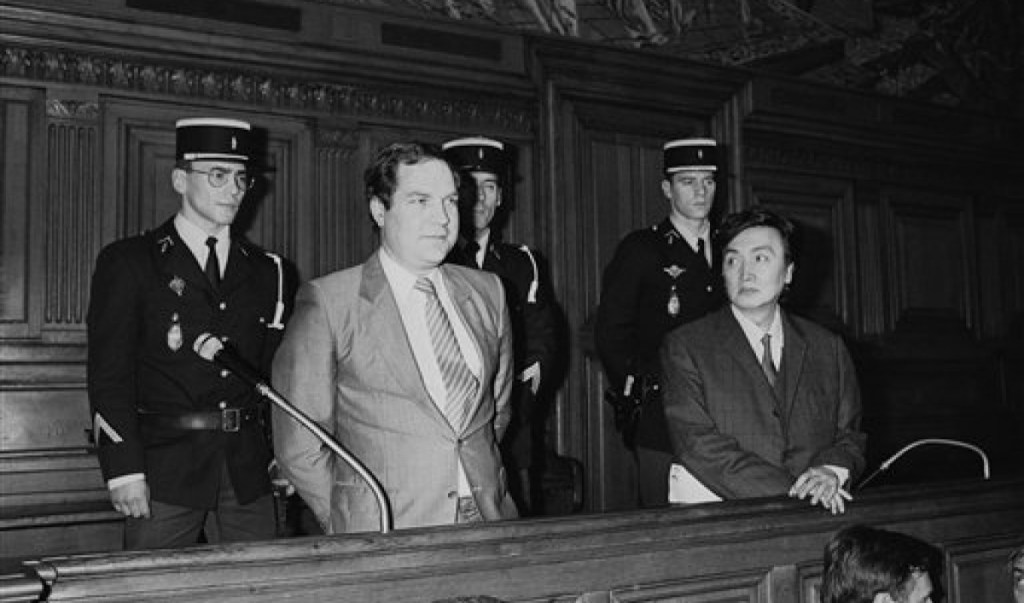 Bernard Boursicout and Shi Pei Pu at court in France, with bailiffs standing behind them.