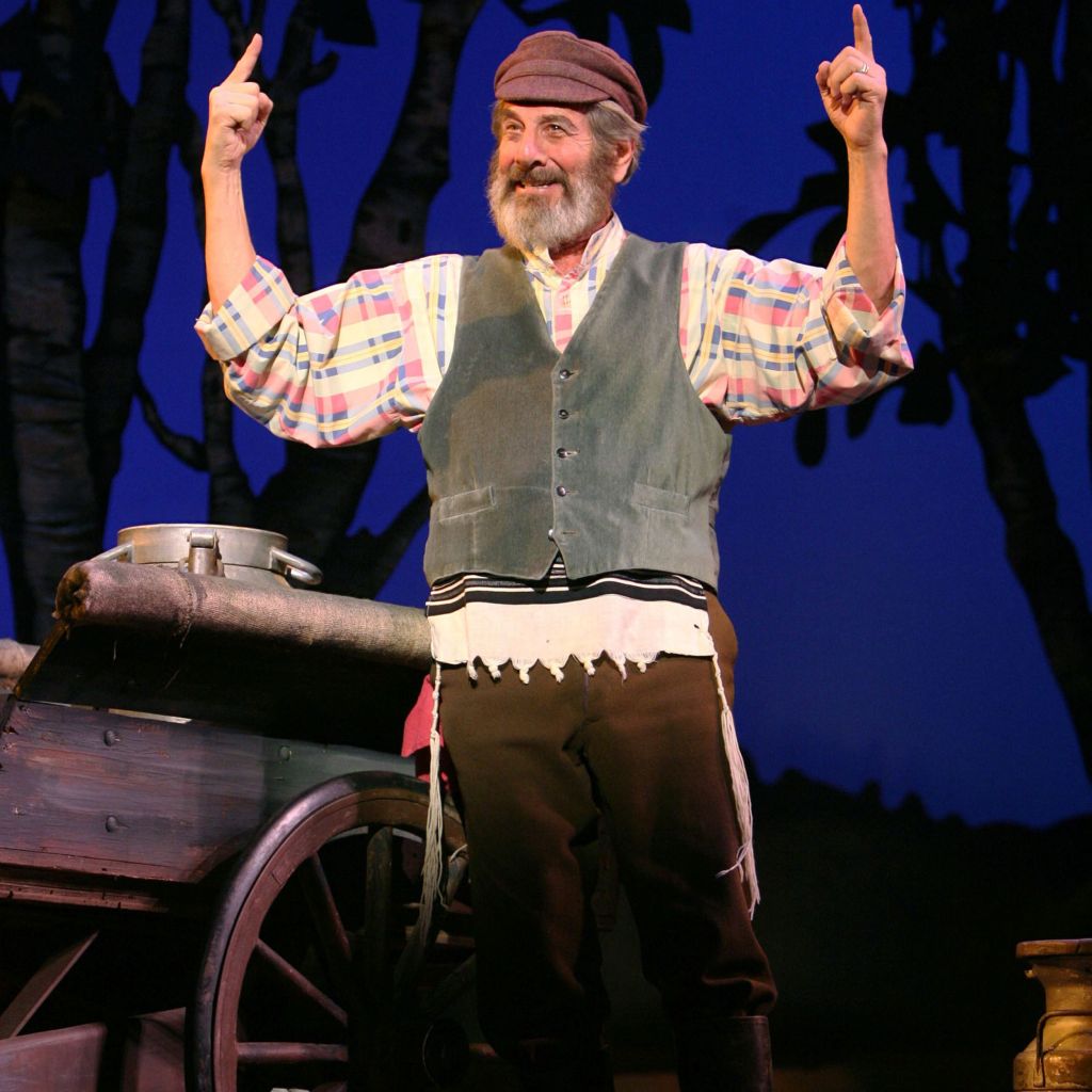 Chaim Topol, in the role of Tevye, gestures happily to the sky.